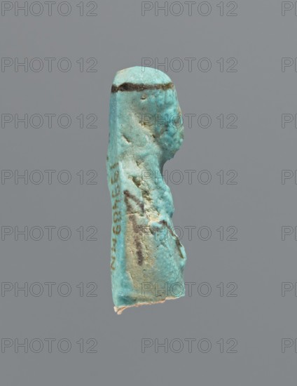 Ushabti, mummy-shaped figurine, preserved head and fragment of torso. Arms crossed on the chest, hands placed at the same level, next to each other, holding hoes in each hand. On the back a square basket is slung on strings over both shoulders. On the head is a long, smooth, tripartite wig with a headband. Triangular face, details almost illegible. Headband and tools painted. ca. 945–ca. 715 BC; Third Intermediate Period, 22nd–23rd Dynasty, Egypt. Ushabti, height 3.7 cm, A small sculpted object in shades of turquoise and aqua with areas of pale beige and darker brownish-green streaks is shown against a plain gray background; the object has an elongated vertical shape with a rounded top and irregular, textured sides, and a slightly rough, uneven surface with a few pits and worn areas; a darker horizontal band runs near the top, and there are several darker spots and streaks along the body, while the lower edge shows a lighter, almost whitish area.