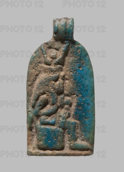 Plaque with a relief image of Isis sitting on a throne, turned to the right and holding infant Horus on her lap; pendant at the top. Amulet plaque, Isis, Horus. Late Period, Egypt, 7th–4th century BC. Height 2.8 cm; width 1.4 cm., A small rectangular pendant with a rounded top and a loop at its peak, showing a carved raised design in worn relief; the surface has a rough, grainy texture with patches of turquoise blue glaze and areas of earthy brown and beige where the glaze is worn or missing; the carved motifs form abstract curved and blocky shapes across the pendant, with smoother blue-glazed areas contrasting with the matte, sandy brown recesses; overall color palette includes turquoise blue, brown, beige, and hints of green.