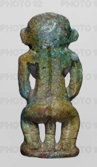 Amulet - Ptah the Dwarf Pataikos, Ptah the Dwarf myth., Egyptian deities, protective amulet, 664–332 BC; Late Period, Egypt, amulet, height 4.5 cm, width 2.2 cm, A small sculpted figurine viewed from the back, showing a humanoid form with a rounded head, broad shoulders, bent arms resting at the sides, a pronounced back and buttocks, and short legs standing on a flat base; the surface shows uneven, pitted texture with areas of corrosion and wear. The visible colors include varied shades of green and turquoise, with patches of bluish-green, darker green-brown, and small areas of reddish-brown and gray.