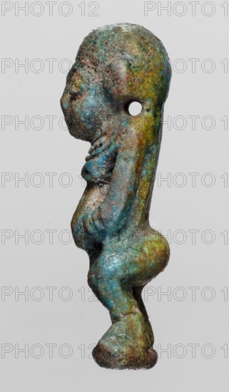 Amulet - Ptah the Dwarf Pataikos, Ptah the Dwarf myth., Egyptian deities, protective amulets, 664–332 BC; Late Period, Egypt, amulet, height 4.5 cm, width 2.2 cm, A small weathered figurine shown in profile with a rounded head, pronounced forehead, and a hole through the upper head; the surface displays a mottled mix of blue, green, brown, and hints of yellow; the face has a small nose and a recessed mouth area; the torso shows a rounded chest, a slightly protruding belly, and a suggestion of arms folded along the front; the lower body narrows into short thighs and ends in rounded feet, with the entire piece exhibiting a pitted, rough texture and areas of patina.