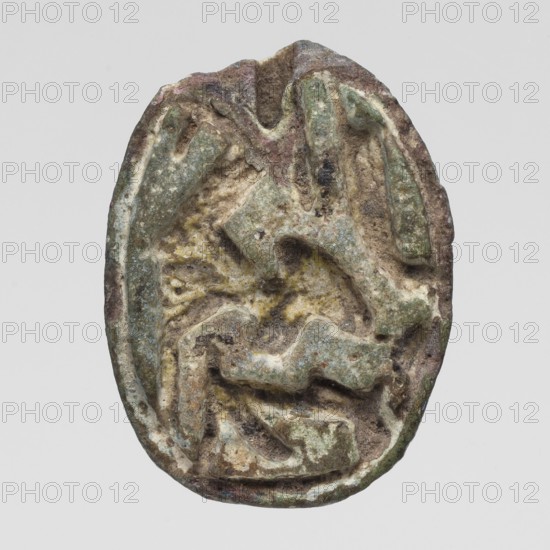 Scaraboid with a monkey. The upper surface is decorated with a convex image of a seated baboon facing right, with the fur on its back marked with crisscrossing lines. On the base is depicted a lying sphinx lion? wearing a feathered crown, above it is a solar disk. In front of the sphinx is the figure of a seated goddess Maat?, above the sphinx's back is visible a lying feather of Maat and possibly another symbol, damaged. c. 1550–c. 1186 BC; New Kingdom, 18th–19th Dynasty, Egypt. Amulet, scaraboid; height 2.3 cm, width 1.7 cm., An oval, weathered object with an uneven, carved surface showing raised and recessed shapes; the surface displays a mix of green, brown, gray, beige, and pale yellow tones with patches of darker brown and small areas of lighter off-white; the edges are worn and irregular, and the overall texture appears rough and pitted with layered ridges and rounded indentations suggesting erosion or age.