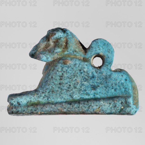 Amulet — ram. Figurine of a ram lying on a flat base, with a loop for hanging on its back. Amulet, material unspecified. Late Period, Egypt, 664–332 BC. Height 2.9 cm; width 1.9 cm. Sacred animal; pendant., A small object shaped like a reclining animal with a raised head and a rounded back, shown against a plain light gray background, appears textured and pitted with a mottled surface in shades of turquoise and aqua with areas of darker blue and greenish tones and some brownish spots; there is a rounded loop near the top with a circular hole, and the underside is flat with similar speckled turquoise coloring and slight discoloration along the edges.
