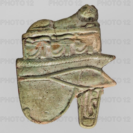 Amulet - Udjat eye with a lioness; maker, Udjat eyes; udjat eye and lioness/uraeus iconography; protective amulet used in grave equipment; ca. 945–664 BC, Third Intermediate Period 22nd–25th Dynasty, Egypt; material: amulet; height 3.6 cm, width 3.8 cm., A greenish, weathered carved object with a textured surface showing a few areas of brownish wear and small dark speckles; the top features a small sculpted animal form in the same green tone, a band with raised decorative motifs runs below it, and a curved protrusion extends to the right ending in a narrow, rounded tab that carries a subtle raised design; overall the object displays irregular edges, chipped beige sections where the underlying material shows, and a patina blending shades of green, beige, brown, and hints of gray.