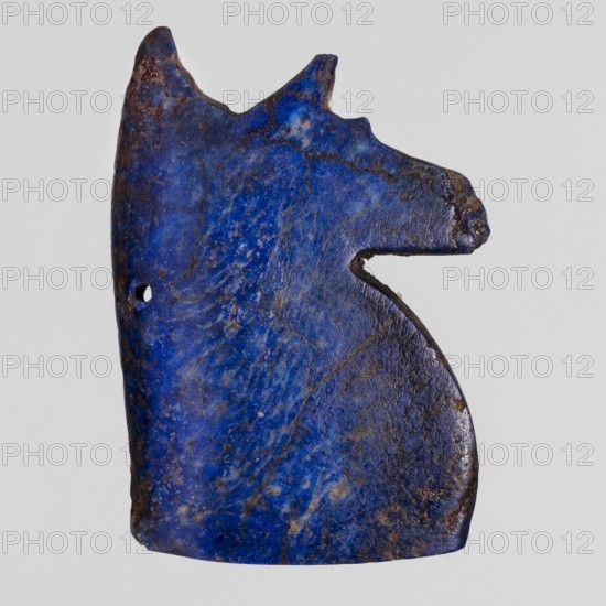 Amulet — Udjat Eye; unknown creator; Udjat eyes; protective amulets; Egyptian religion; grave goods; ca. 1550–1295 BC; New Kingdom, 18th Dynasty, Egypt; amulet; height 3.6 cm; width 3.8 cm, A blue, irregularly shaped object with a textured surface showing areas of darker and lighter blue and some brownish spots, with a notch on one side and a small hole near the edge, against a light gray background.