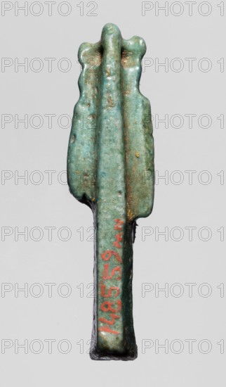 Amulet — figurine of a lion-headed goddess, lionesses, Egyptian deities; Sekhmet, Wadjit, Bastet ; lion-headed goddess with a lotus scepter in her left hand right lowered. 664–332 BC, Late Period, Egypt. Amulet; height 4 cm, width 1 cm, depth 1.2 cm., A small elongated object with a rounded top that has a lobed edge and three raised central ridges, showing a weathered surface in shades of green and turquoise with areas of brownish discoloration and small patches of darker green; the lower portion narrows into a straight stem with a darker underside and a small area of red pigment on one side; the background is a uniform light gray.