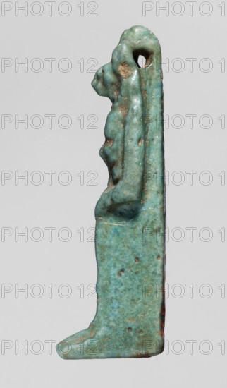 Amulet — figurine of a lion-headed goddess; lionesses; Egyptian deities; Sekhmet ; Wadjit ; Bastet ; lion-headed goddess holding a lotus scepter in her left hand right lowered; 664–332 BC, Late Period, Egypt; amulet; height 4 cm, width 1 cm, depth 1.2 cm., A slender vertical figurine rendered in a mottled turquoise-green with areas of darker green and brownish spots, shown in profile against a neutral light gray background, with a rounded head featuring a small circular hole near the top, a pronounced nose and chin, a suggestion of a torso and bent arm, a long straight back and skirt-like lower section ending in a flat foot, and a slightly rough, pitted surface texture.
