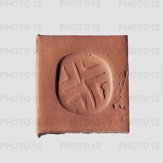 Stamp seal with geometric ornament. A prism-shaped stamp seal with rounded edges and an oval, nearly rectangular base. A hole is drilled through the longer diagonal side walls transverse to the longitudinal axis of the stamp. On a flat base is carved a shallow geometric ornament consisting of regularly spaced, slightly open hooks: two large hooks with their tips touching in the center and four small hooks in triangular fields between the arms of the large hooks. Materials: seal. Culture/Date: Halaf culture, c. 6th–5th millennium BC ca. 6000–5000 BC. Place of origin: Northern Mesopotamia Iraq/Syria/Turkey. Dimensions: height 0.8 cm; width 1.5 cm; depth 1.7 cm; hole diameter 0.2 cm. Creator: unknown., A square piece of reddish-brown clay or terracotta with a circular impression in the center containing a simple carved cross-like pattern, sitting on a light gray background; the square shows rough edges and small surface cracks and texture, with visible variations of reddish-brown and subt...