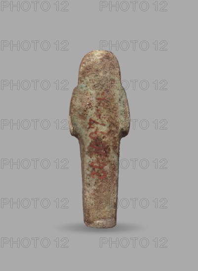 Ushabti, Mummy-shaped funerary figurine, ushabti. Arms crossed on the chest, hands arranged in a line next to each other, holding hoes in both hands; slightly convex tools. Long, three-part smooth wig, ears uncovered. Round face, facial details illegible. Not inscribed. ca. 1069–715 BC; Third Intermediate Period, 21st–23rd Dynasty, Egypt. Height 5.5 cm, width 1.8 cm., A single upright statuette-shaped object with a rounded top and a narrower base, shown against a plain gray background; the object has a weathered surface with mottled tones of brown, green, and pale turquoise, with some areas of reddish discoloration and lighter beige patches, and its texture appears rough and pitted.