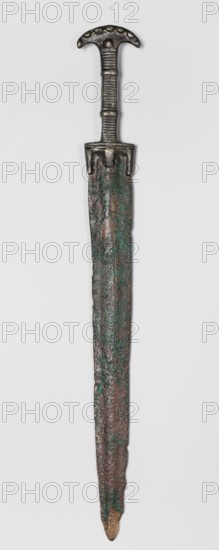 Double-edged sword, Bosporan workshop. Short sword, cast in one piece. Double-edged blade with a centric point; a prominent bulge runs through the center of both faces. Hilt divided into three segments: a crescent-shaped pommel decorated on both sides with small oval knobs imitating rivet heads, with one such knob on each side at the transition to the hilt shaft; b square-section shaft decorated on two opposite sides with horizontal incisions, with two convex flat bands surrounding the shaft in places and a guard at the base of the blade; c guard in the form of a horizontal profiled strip from which three protrusions emerge — two longer ones along the blade line and one shorter on the axis extension. 6th century BC; Black Sea region; weapon. Height 45.3 cm, width 5.6 cm, depth 1.7 cm, weight 0.566 kg, length 45.5 cm., A long metal object resembling a blade with a handle, shown vertically against a light gray background, with a rounded top handle that has a textured grip and a curved cr...