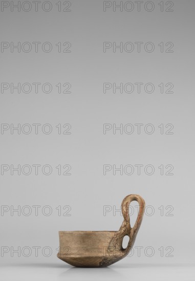 Miniature kyatos, A miniature kyatos with a flat bottom and a bowl whose walls widen diagonally almost halfway up and then become vertical. Where the walls break, a sharp protrusion remains on the outer side the diameter of the upper part is smaller than the lower. The vertical handle is strongly extended upwards, attached to a protrusion on the body and to the spout, with a crossbar above the spout's edge. On the outer side the handle has a ribbon shape, then from the top widens inward with an undercut above the spout. The undercut part is decorated with engraved vertical lines. Engraved lines are also found on the bottom arranged in a grid and under the base of the handle in the shape of an X. The upper surface of the edge on the body is decorated with diagonal engravings; the lower part of the vertical walls with recessed dots. Both rows are separated by a horizontal engraved line. Early 7th century BC, Caere; vessel; height 6.3 cm, width 7.7 cm., A small shallow vessel in earthy br...