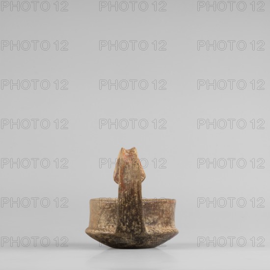 Miniature kyatos, A miniature kyatos with a flat bottom and a bowl with walls widening diagonally almost halfway up and then vertical. Where the walls break, a sharp protrusion is left on the outer side the diameter of the upper part is smaller than the lower. The vertical vise is strongly extended upwards, attached to a protrusion on the body and to the spout, with a crossbar above the spout's edge. On the outer side, it has a ribbon shape, then from the top widens inward with an undercut above the spout. The undercut part is decorated with engraved vertical lines. Engraved lines are also found on the bottom arranged in a grid and under the base of the vise in the shape of the letter X. The upper surface of the edge on the body is decorated with diagonal engravings, the lower part of the vertical walls with recessed dots. Both rows are separated by a horizontal engraved line. Early 7th century BC, Caere, vessel, height 6.3 cm, width 7.7 cm, A small earthenware vessel sits centered on ...