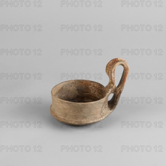 Miniature kyatos, A miniature kyatos with a flat bottom and a bowl whose walls widen diagonally almost halfway up then become vertical. Where the walls break, a sharp protrusion remains on the outer side the diameter of the upper part is smaller than the lower. The vertical vise is strongly extended upwards, attached to a protrusion on the body and to the spout, with a crossbar above the spout's edge. On the outer side it has a ribbon shape, then from the top widens inward with an undercut above the spout. The undercut part is decorated with engraved vertical lines. Engraved lines are also found on the bottom arranged in a grid and under the base of the vise in the shape of the letter X. The upper surface of the edge on the body is decorated with diagonal engravings; the lower part of the vertical walls with recessed dots. Both rows are separated by a horizontal engraved line. Early 7th century BC, Caere; vessel; height 6.3 cm, width 7.7 cm., A small shallow bowl with a rounded base an...