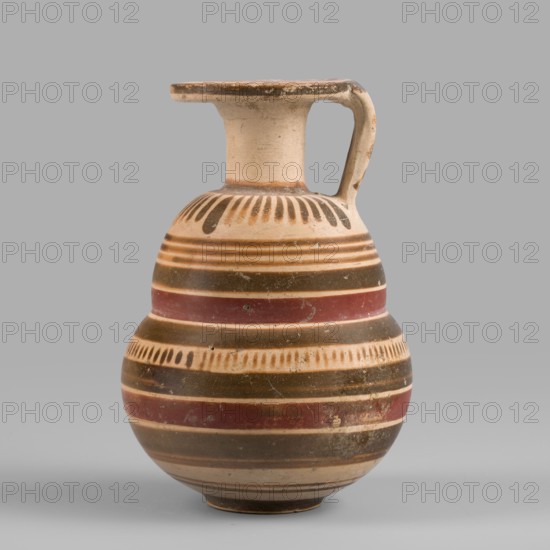 Italo-Corinthian aryballos, geometric motifs, Etruscan pottery, 600–575 BC, Etruria, aryballos vessel, weight 0.054 kg, height 7.7 cm, diameter 5.3 cm, A rounded ceramic vessel with a narrow neck and a flat, wide rim connected to a single handle, shown against a neutral gray background; the surface of the vessel displays horizontal bands and decorative motifs in cream, brown, dark brown, and reddish tones, with a pattern of short vertical strokes near the shoulder and a repeating band of short vertical marks around the midsection; the rim and handle show wear and slight discoloration, and the vessel has a smooth, slightly aged finish with small surface blemishes.