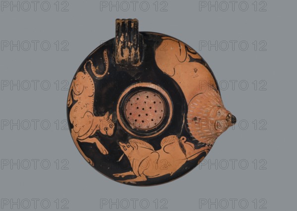 Red-figure guttus, Arsinoe Cyprus, 5th BC, Attica. Guttus vessel, height 5.1 cm, width 10.6 cm. Flat bottom, one vertically mounted vice, narrow, with four ridges; circular in shape with a slightly distinct foot. Lion's muzzle plastically formed to form a rim. Decoration: a lion, a panther, and a boar on the shoulders; cats iconography, boar iconography, lion iconography. Technology: visible traces of turning; matte, dense, good-quality varnish. Clay purified with a small amount of admixtures mica. Notes: the vise is glued; small and rare secondary chips visible on the varnish surface. Clay color: ~2.5 YR 6/6 light red. Varnish color: 10 YR 2/1 black., A round ceramic object viewed from above against a gray background, predominantly black and terracotta in color, with a central recessed circular area pierced with several small holes and surrounded by a raised rim; a small ribbed handle projects from one edge and a three-dimensional animal head protrudes from the opposite edge, both sho...