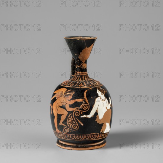 Aryballus lekythos. An aryballus lekythos on a ring-shaped, profiled foot, with a bulging, egg-shaped belly, convex handles flowing into a neck terminating in a cup-shaped rim. The vise is narrow and band-like. At the base of the neck is a bar ornament, and on the handles is an egg-shaped motif with plastic lines in ovals. Below the vise are two upward-facing palmettes, arranged one above the other, decorated with leaves and volutes. The front of the vessel depicts a seated, nude woman wearing a garment covering her legs and hips; she faces left with her head turned right. Behind her is a leaning, winged Eros, standing on his right leg with his left leg raised, holding a necklace in his outstretched hands. The composition is framed from below by an egg-shaped motif. Preservation condition: The neck, vise, and rim are glued; a few chips are visible on the surface. Ca. 420 BC earlier dating: 4th century BC. Apulia. Lekythos aryballus lekythos. Vessel dimensions: height 9.4 cm; width 5.0 ...