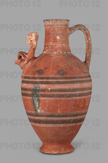 Jug with a figurine of a woman with a jug. Cypriot pottery, female figurines applique. Jug on a foot resembling an inverted echinus with a belly widening by convex shoulders, separated from a cylindrical neck with a straight spout. A two-part vise connects the neck with the shoulders, and on the side opposite the vise is the bust of a woman with a jug. Decoration executed in white and black paint: the belly at its widest point and along one-third of its height is decorated with alternating white and black concentric bands; beneath the vise a wavy black stripe extends onto the shoulders on both sides; shoulders feature two birds among plants, a row of dots and a concentric stripe at the base of the neck; a branch with leaves encircles the neck above, and black triangles on a white background at the edge. 480–400 BC; Cypriot — Classical Period I. Arsinoe Marion. Vessel. Height 35 cm, width 19 cm, weight 1.72 kg., A terracotta jug with a rounded body and narrow neck sits against a plain g...