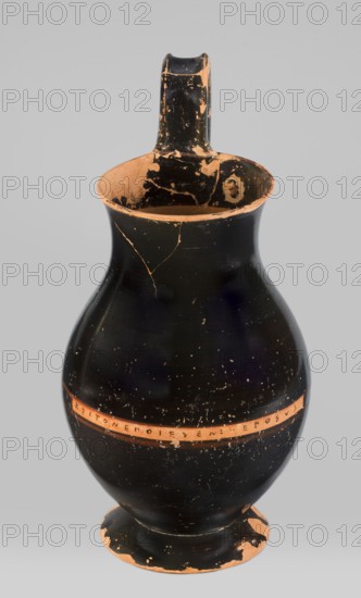 Olpe type of jug for liquids with inscription. Unknown Attic workshop; Crito ca. 550–500 BC. Black-finished olpe with a clay-coloured cartouche at the point of maximum diameter bearing Crito's signature KRITONEPOIESEN: VEGOSUS, Krito prepared by. LEPOSYS.... Medium-sized olpe, rim edge slightly turned outwards; low neck gently transitioning into a concave, spherical belly, clearly distinguishable from the low conical foot with a recess. Bottom slightly convex. Profiled handle with clearly distinguishable edges. On the inner side of the rim two clay nodules one reconstructed are visible, located 4.5 cm apart on the side of the handle. Dated 550–500 BC. Origin: Attica, Athens. Vessel olpe. Height 26 cm, width 13.5 cm, depth 15.5 cm, weight 0.58 kg., A rounded ceramic vessel with a narrow neck and a single handle, showing chipped areas that reveal an underlying terracotta color beneath a predominantly black surface; the rim and interior show worn terracotta and black patches, and the body...