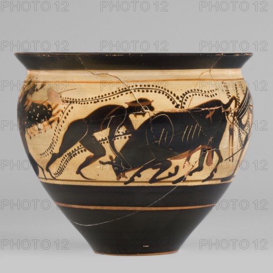 Black-figure skyphos with depictions of Athena and Heracles fighting the Cretan Bull, Heracles taming the Cretan bull; Athena also depicted. Early 5th century BC, Attica. Skyphos vessel, thin-walled, height 8.6 cm, width 10.2 cm, weight 0.15 kg. Physical description: Wide rim flaring outward distinct from the body; deep bowl, convex in upper part, tapering to small diameter with slightly concave base. Interior: reserved edge band 1–2 mm with an uneven strip around vessel; interior surface largely covered with black varnish, edges with uneven varnish. Technology: Cleaned, homogeneous clay, uniformly fired; high-quality matte varnish applied in an even layer but unevenly fired greenish tint on rim. Traces of turning visible under varnish; smooth surface; admixtures mica? visible in interior varnish. Condition: secondary losses, visible remains of conservation treatments; glued. Attributed note: Kamila Nocon., A rounded ceramic vessel with a flared rim decorated in a black-and-beige color...