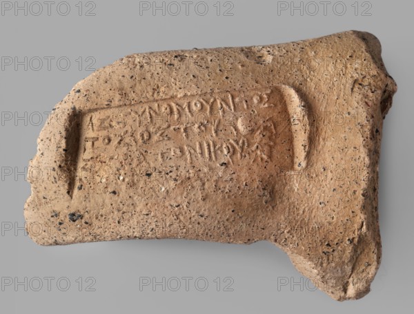 Fragment of a stamp from a Sinopean transport amphora with the stamp of the astynomeus Posis, son of Stratonikos. Rectangular four-line stamp; the last line is not impressed. First line contains the astynomenic title; second and third lines contain the astynomeus' name and patronymic; the fourth line contained the amphora manufacturer's name. To the right of the legend, at the height of the second and third lines, is an emblem in the form of a helmeted head of Athena. Inscription reading Made when Posios son of Stratonicus was astynomeus. Dated 320–300 BC previously dated ca. 150–100 BC. Provenance: Sinope origin; Myrmekion finding. Stamp fragment vice. Dimensions: height 7.2 cm, width 6 cm, depth 2.3 cm., A fragment of a rough, porous object in shades of light brown and tan with darker speckles sits against a neutral gray background; the surface shows an indented rectangular area with carved grooves and shallow depressions, and the edges are irregular and broken, revealing textured, g...