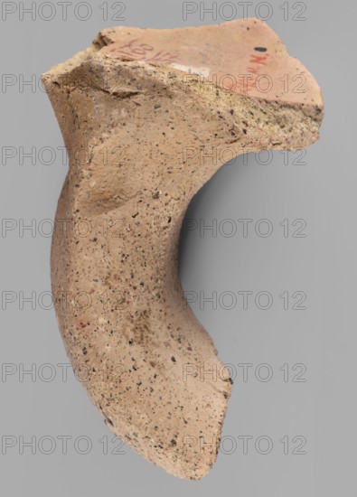 Fragment of a vice from a Sinopean transport amphora with a rectangular four-line stamp. The last line is not impressed. First line contains the astynomenic title; second and third lines contain the astynomeus' name and patronymic Posis, son of Stratonikos; fourth line contained the amphora manufacturer's name. To the right of the legend, aligned with the second and third lines, is an emblem of a helmeted head of Athena. Inscription reading Made when Posios son of Stratonicus was astynomeus. Date: 320–300 BC previously dated ca. 150–100 BC. Provenance: Sinope origin, found at Myrmekion Crimea. Stamp on amphora vice. Dimensions: height 7.2 cm, width 6 cm, depth 2.3 cm., A broken curved ceramic fragment with a rough, porous texture in shades of light tan and beige with small dark speckles, showing uneven, jagged edges and a slightly lighter interior surface, set against a neutral gray background.