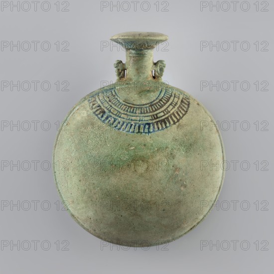 New Year's Canteen, A flat faience canteen with a belly resembling two flattened spherical segments joined at their edges; a smooth tape-like band runs along the joint. The thin neck ends with a spout shaped like an open papyrus cup. Small handles on both sides of the neck are shaped as stylized monkeys baboons. The upper part of the belly is decorated with an impressed, stylized design resembling a necklace. 664–525 BC; Late Period, 26th Dynasty, Egypt. Vessel; height 12.3 cm, width 10 cm, depth 5.7 cm., A round, flat vessel with a short neck and flared rim, shown against a plain light gray background; the vessel surface is textured and predominantly green with areas of lighter and darker green and small patches of tan and brown; near the neck there is a decorative band in darker blue-green tones forming a semicircular pattern with repeated vertical strokes; the neck has a pair of small, symmetrical protrusions on either side and the rim shows slightly darker edging in muted green and...