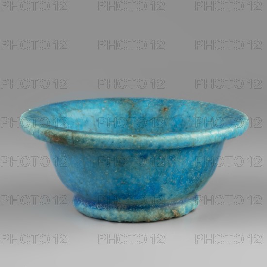 Bowl, Goluchów Greater Poland Voivodeship, faience vessel, bowl with a slightly rolled-up rim on a ring-shaped foot, made of faience covered with a blue glaze. 332–30 BC; Ptolemaic Period, Egypt. Vessel; height 4 cm, width 10 cm., A shallow rounded bowl with a rolled rim and a short foot, made of a mottled blue material showing variations from bright turquoise to deeper cyan with areas of greenish and darker blue veining and some small brownish spots and mottling, set against a neutral grey background.