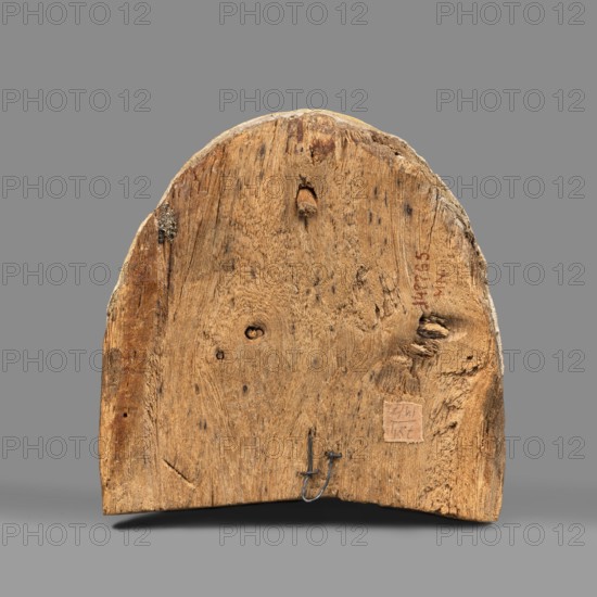 Woman's sarcophagus mask. Mask of wood covered with a layer of canvas to which paint is applied. The face is wide, painted with yellow paint. Large, almond-shaped eyes, the pupils highlighted with black paint, arched eyebrows. Straight nose, flattened at the tip. The mouth and the protrusions of the chin are marked in red, as is the outline of the eye sockets above the eyes. Face height: 15 cm. 1st–2nd century; Roman period 4th century AD, Egypt. Sarcophagus mask, height 15 cm, width 14.3 cm, depth 8 cm, weight 0.454 kg., A roughly semicircular piece of wood with a weathered, textured surface showing grain patterns, knots, and small holes, resting against a plain background; the wood displays shades of brown and tan with darker brown spots and some grayish areas at the edges, and a small metal hook embedded near the lower edge.