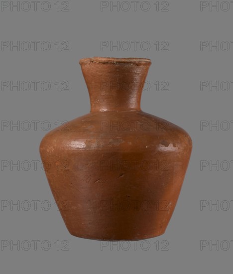 Jug, ceramics, Egyptian pottery, clay vessel, medium-sized jug with a biconical body. Vessel is widest at about half its height; wide shoulders, not very sloping. Wide, almost cylindrical neck widening towards the spout, its height about 1/3 of the vessel. Profiled, irregular spout, slightly raised and extended on one side, forming a small spout. Spout nearly triangular in cross-section, with an approximately millimeter-sized cylindrical bulge on the outer profile. Bottom almost flat, very slightly rounded. Made of Nile clay NB1 Vienna System. Neck likely made separately and connected to the shoulders. Outer surface leveled, covered with an engobe and polished. Inner surface leveled except for the neck, which was also covered with engobe and polished. Color reddish-brown. Quite well preserved; rim slightly chipped in two places and engobe worn off in places on the outer surface. Dated to the 6th Dynasty; Old Kingdom, Edfu. Comparable vessel: height 20.5 cm, rim diameter 8.5 cm, body di...