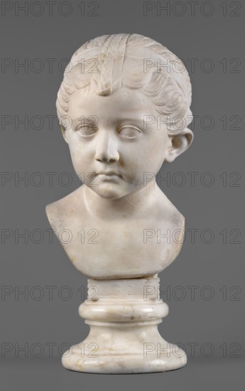 Portrait of a princess from the Julio-Claudian dynasty Julia?, unknown Roman workshop. The bust depicts a girl with a round, rather chubby face, turned slightly to the right; a rounded, elongated chin, and small, slightly pursed lips with a pronounced, wavy line of the upper lip. The almond-shaped, smooth eyes are rather shallowly set, with marked upper eyelids and barely visible eyebrows. The ears are carefully styled. The wavy hair is combed up and tied with a headband. At the back of the head, the hair is tied in a bun and a braid that falls down the middle of the head onto the smooth forehead. End of the 1st century BC–beginning of the 1st century AD, Roman Empire. Sculpture; height 25.7 cm, width 16 cm, depth 12.5 cm, weight 11.5 kg., A marble bust of a child displayed against a gray background, showing a head and upper shoulders on a rounded pedestal; the sculpture has smooth carved hair with a headband and stylized waves, softly modeled facial features with closed or minimally d...