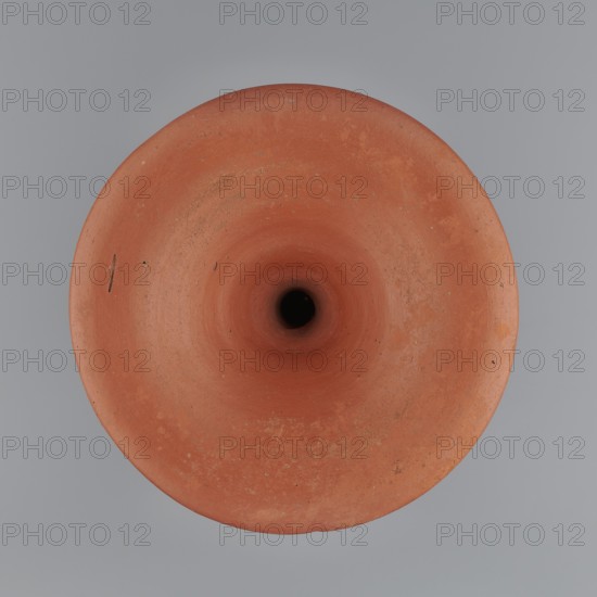 Bowl base. Base for a vessel with an almost equal diameter of both rims; both rims are irregular with a wavy line. The center of the base is empty. The narrowest part of the base is approximately 2/3 of the height of the entire vessel. Vessel made of Nile clay NB1. Surface leveled and covered with an engobe, then polished. Vessel color: red. Complete vessel, very well preserved. c. 2494–c. 2181 BC; Old Kingdom, 5th–6th Dynasty, Edfu. Vessel; top diameter 17.5 cm, bottom diameter 18 cm, height 25.6 cm, weight 1.30 kg., A top-down view of a round terracotta object with a central dark hole, showing a smooth funnel-like interior and rim with some surface speckles and small imperfections, set against a smooth gray background; the visible colors are reddish-brown, dark brown to black in the center, and gray.