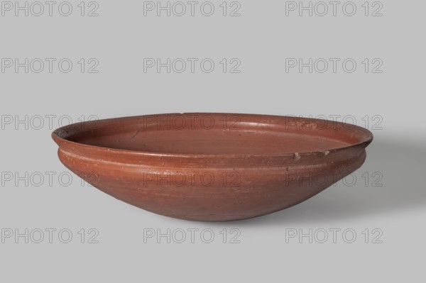 Medum-type bowl, Egyptian pottery, Medum-type bowl, clay vessel. Bowl with a hemispherical shape narrowing just below the rim to form a carination. Rounded bottom. Straight, slightly widening spout whose diameter is slightly larger than the shoulders. Even surface covered with a red engobe and polished. Vessel color: red. Fairly well preserved with minor losses on the rim. c. 2494–c. 2181 BC; Old Kingdom, 5th–6th Dynasty, found at Edfu. Vessel; height 7 cm, spout diameter 26.4 cm, weight 0.90 kg., A shallow, round ceramic bowl in reddish-brown with a slightly darker interior rim and subtle variations in tone across its surface, showing a few small chips and worn areas along the rim and outer body, resting on a light gray background with soft shadow beneath it.