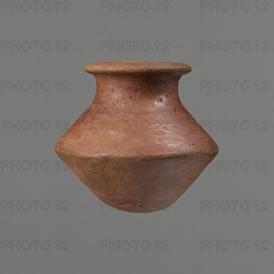 Vessel, Egyptian pottery ceramic clay vessel, c. 1650–c. 1550 BC Second Intermediate Period, Edfu, vessel, height 7.4 cm, rim diameter 5.5 cm, belly diameter 8.2 cm., A single terracotta vessel with a rounded, bulbous body and a flaring neck and rim floats against a plain grey background; the surface shows an earthy reddish-brown color with patches of lighter tan and ochre, a slightly rough and weathered texture with visible small pits, scratches, and subtle variations in sheen, and the rim appears flatter and slightly darker than the middle of the vessel.