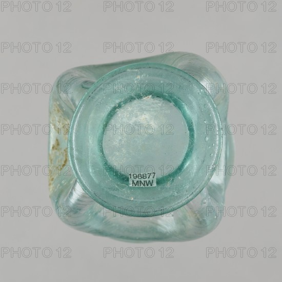 Glass cup; maker, Egypt; 1st–2nd century AD. Type: Isings form 32. Transparent bluish-green glass. Cup with a slightly flaring spout, decorated with four oval concavities on the belly. Ring-shaped foot with a clearance made by pressing the bottom inward; free-blown. Outer diameter of the spout: 6.10 cm. Height: 9 cm. Belly diameter: 6.70 cm. Outer diameter of the bottom: 4.60 cm. Vessel; weight 0.054 kg., A translucent pale green glass vessel shown from above with a circular top surrounded by a thicker rounded rim, a few areas of surface wear and small patches of residue on the glass, and a group of slightly curved tubular supports forming the body visible beneath the rim against a neutral light gray background.