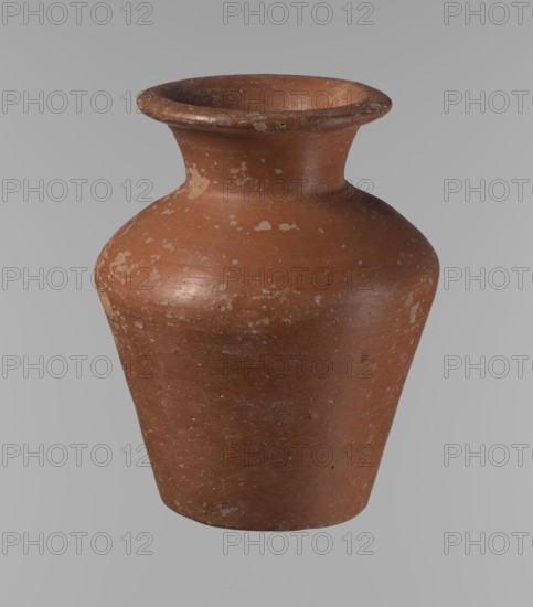 Vessel, Egyptian pottery, clay vessel: a conical vessel, widest at approximately 3/4 of its height. Shoulders quite wide, almost horizontal—slightly sloping. Wide, short, funnel-shaped neck widening towards the spout. Spout wide, flat in the upper part, slightly rounded at the bottom, slightly asymmetrical. Bottom slightly convex, asymmetrical. Surface even. Lower part worked to approximately 2/3 of its height with a knife or similar tool. Outer surface and inner surface of rim and neck covered with a layer of dark red engobe. Vessel color dark red. Vessel complete; surface eroded in many places, numerous clay chips on the rim. Ca. 2686–ca. 2181 BC; Old Kingdom, Edfu. Vessel height 16.7 cm; rim diameter 9.5 cm; body diameter 13 cm; bottom diameter 8.1 cm. References: Reisner, Mycerinus, p. 219, types XIX and XX, fig. 69., A single rounded ceramic vessel with a flared rim and narrow neck sits against a plain background; the surface shows worn patches and speckled areas with a textured, ...
