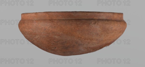 Medum-type bowl, A small Medum-type bowl with characteristic carination under the rim. Rounded bottom. Arched walls, gently breaking towards the center of the vessel around 2/3 of its height. Straight, perpendicular rim. Narrow, sloping shoulders. The diameter of the rim is significantly smaller than the diameter of the vessel's arms. Clay probably NB2. The vessel's surface is leveled and covered with a layer of engobe, and then polished. Vessel color: red. c. 2686–c. 2181 BC; Old Kingdom, Edfu. Vessel; height 4.5 cm, diameter 11 cm rim, diameter 11.6 cm arms., A rounded, shallow bowl shown from the side with a curved rim and smooth, slightly textured surface in shades of reddish-brown and terracotta, with visible small dark specks and lighter worn patches; the background is a uniform light gray.