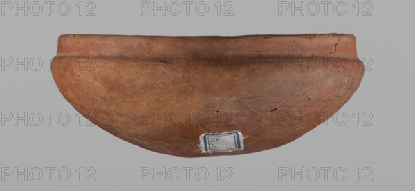 Medum-type bowl, A small Medum-type bowl with characteristic carination under the rim. Rounded bottom. Arched walls, gently breaking towards the center of the vessel around 2/3 of its height. Straight, perpendicular rim. Narrow, sloping shoulders. The diameter of the rim is significantly smaller than the diameter of the vessel's arms. Clay probably NB2. Surface leveled and covered with a layer of engobe, then polished. Vessel color: red. c. 2686–c. 2181 BC; Old Kingdom, Edfu. Vessel; height 4.5 cm, diameter 11 cm rim, diameter 11.6 cm arms., A reddish-brown rounded clay vessel with a slightly flared rim, showing surface texture, small chips, and cracks, set against a plain light gray background; a small rectangular patch with worn edges and a bit of dark framing is visible on the lower outer surface.