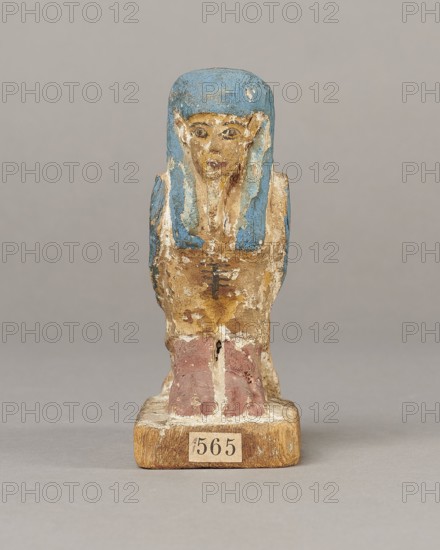 Figurine of the Soul of Ba, Ba mythology; birds, djed pillars, wigs, beards, feathers; The figurine has carefully carved and painted facial details and a reproduced arrangement of feathers on the wings. On the head is a tripartite wig painted blue. On the chest below the wig is a depiction of a djed pillar. Straps supporting a false beard are painted along the cheeks. The figurine's disproportionately large feet rest on a rectangular base. 664–332 BC, Late Period, Egypt; wood figurine, height 11 cm, width 9.5 cm, depth 4.5 cm., A small painted figurine of a seated human-like figure shown from the front, with a blue headpiece and blue accents along the sides of the head, a face painted in beige tones with darker details for features, a torso in worn beige and brown paint with traces of darker markings, and lower legs painted in muted reddish-brown sitting on a rectangular wooden base that is light brown; the background is a uniform light gray.