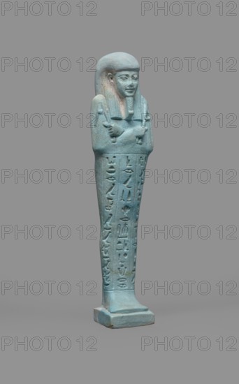 Udja-hera shabti, Udja-hera ca. 380–343 BC. Mummy-shaped funerary figurine shabti from Egypt, Late Period, 30th Dynasty. Height 15.5 cm, width 3.9 cm. Standing on a base with back supported by a pillar. Arms crossed on the chest, right folded over left, elbows and shoulders subtly marked. Holds hoes in each hand; handles slightly curled. Right hand also holds a twisted rope from which a basket is slung over the left shoulder; convex tools and engraved basket. Wears a long three-part wig combed into narrow strands ending in borders; long slightly tapering curled beard; large ears; proportionate, carefully crafted facial features with a slight smile. Inscription engraved in three columns separated by lines on the front of the figurine's legs. Associated motifs: wigs, hieroglyphs, hoes, beards, Book of the Dead, grave goods; function as funerary figurine/Mummy-shaped figurine. Provenance: purchase., A turquoise-blue statuette of a standing human figure with a long wig and a small beard, a...