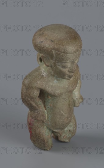 Amulet - Ptah-dwarf Pataikos, Ptah-dwarf mythology. Figurine of a naked dwarf man with a large head with a wide forehead, short arms with clenched fists pressed to the hips, and short legs broken off at the knees. Careful modelling. 7th–4th century BC; Late Period, Egypt. Figurine, amulet. Height 6.5 cm; width 3.7 cm; depth 2.6 cm., A small sculpted figure standing on a plain gray background, with a rounded head and simplified facial features, a compact torso, and short limbs; the surface shows a weathered, mottled texture with shades of brown and green and hints of darker spots, and a small area of reddish coloration on one leg; the figure appears solid with smooth worn contours and subtle variations of pale greenish patina and brownish earth tones across its form.