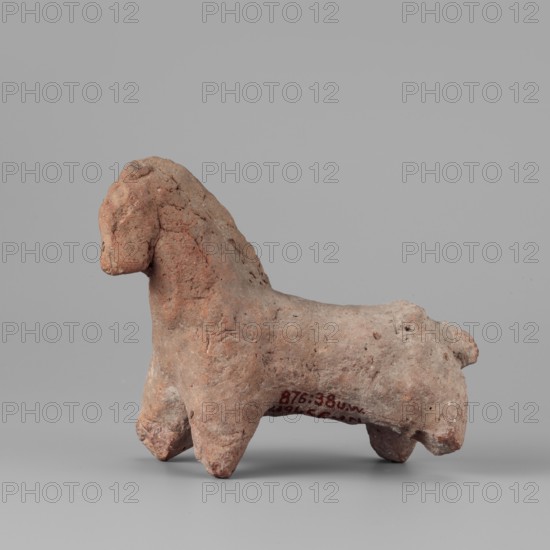 Horse figurine, horses, 664–30 BC; Late Period–Ptolemaic Period, found at Edfu, figurine, height 8 cm, width 10 cm, A small rough-textured sculpted figure of an animal with a rounded head, short neck, sturdy body, and four thick legs, shown in profile on a flat surface; the figure's surface has uneven, pitted areas and visible cracks. Colors visible include shades of reddish-brown, terracotta, light brown, and small patches of pale gray, set against a neutral light gray background.