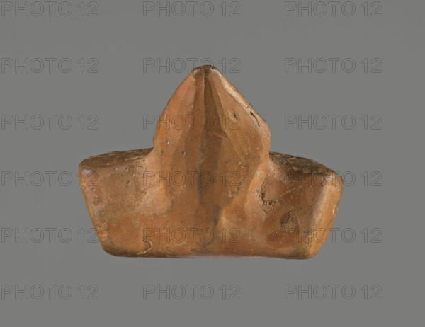 Oil lamp, unknown Pannonian workshop. Oil lamp with leaf ornament, Roman three-burner lamp. Mold-made rectangular flat vessel. Rectangular recessed disc surrounded by stylized egg-shaped ornament. Three olive holes placed at regular intervals within the disc. Leaf-shaped handle on the long side. Opposite side has three short circular burners with large charred wick holes. 1st–2nd century, Pannonia. Height 3.3 cm, width 7.3 cm, depth 5.1 cm., A small brown clay object with an irregular, somewhat triangular central peak and broader base, showing uneven surfaces, small pits, and worn edges; the clay ranges from light to darker brown with subtle reddish and ochre tones, and there are a few small darker spots and scuffs on its surface, all set against a uniform gray background.