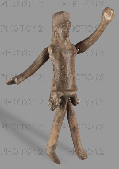 Doll with movable limbs, unknown Corinthian workshop author ?, restitution provenance, toys, dolls, human figurines, 500–450 BC, Corinth place of origin ?, figurine; height 13.9 cm, width 4.1 cm, depth 1.9 cm, weight 0.05 kg, A worn figurine of a humanlike form stands against a plain background, showing a weathered surface in shades of brown with patches of lighter tan and small areas of pale discoloration; the figure has an elongated torso and a simple head with a suggestion of facial features and a rounded cap or headdress, a few irregularities and rough spots across the body, two long, slightly bent arms with one raised and the other extended outward, and a skirtlike lower section from which two long legs extend and taper to rounded feet; there are traces of darker brown smudging and some whitish residue in a few crevices, and soft shadowing falls to one side on the neutral background.