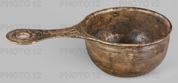 A ladle with a handle decorated with a depiction of Mercury, Mercury myth., Roman deities, ladles, 1st century, Roman Empire 27 BC–476, vessel; height 6.5 cm, width 25 cm, depth 13.5 cm, weight 0.62 kg, A metal ladle with a rounded bowl and an elongated handle is shown against a neutral light gray background; the object displays a worn, mottled surface with a mix of brown, bronze, dark brown, greenish patina, and hints of black, and the interior and exterior of the bowl show textured pitting and discoloration; the handle features a decorative circular end with raised swirling motifs and a central hole, and the handle surface shares the same aged, speckled coloration as the bowl.