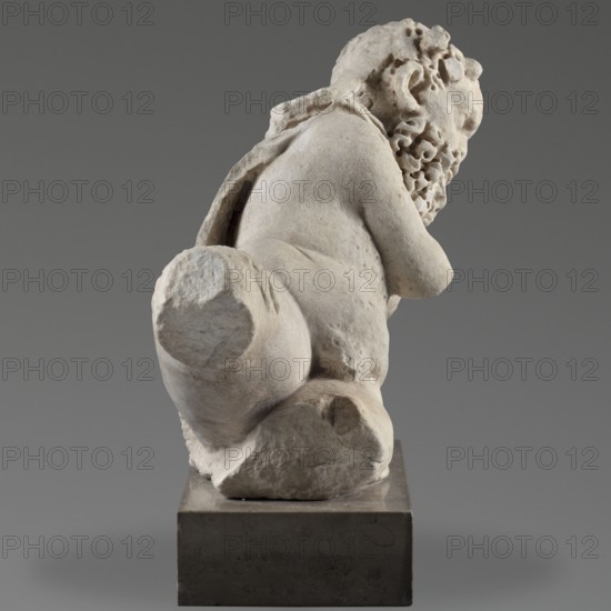 Reclining Silenus, unknown Roman workshop, architectural elements, Silenus mythology, Roman sculpture, Sculpture of a reclining Silenus supported on his left hip and elbow, 69–79, Roman Empire 27 BC–476, sculpture, height 29.4 cm, width 37 cm, depth 22 cm, weight 19.4 kg, A pale off-white stone sculpture of a seated figure viewed from behind, showing a rounded back, shoulders, and a curly textured head and beard on one side; the figure rests on a rough stone base that sits atop a darker rectangular plinth. The background is a smooth neutral gray. Colors visible include off-white, beige, light tan on the sculpture and base, and dark gray on the plinth and background.
