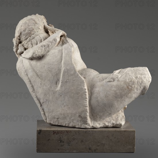 Reclining Silenus, unknown Roman workshop, Scen.Gal.Class., architectural elements, Silenus mythology, Roman sculpture — Sculpture of a reclining Silenus supported on his left hip and elbow, dated 69–79, Roman Empire 27 BC–476, sculpture; height 29.4 cm, width 37 cm, depth 22 cm, weight 19.4 kg, A weathered pale stone sculpture of a reclining figure is shown from a rear-quarter angle, resting on a rectangular darker stone base; the sculpture displays textured carved hair and draped cloth with visible folds and ridges, and a rounded limb extending outward; the colors visible are shades of off-white and light gray on the sculpture, darker gray on the base, and a neutral medium gray background.