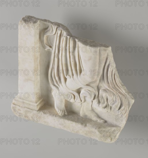 Fragment of a relief with a dancing maenad, 1st century BC, 27 BC–14 period of the rule of Octavian Augustus, Roman Empire, bas-relief, height 35 cm, width 30 cm, thickness 6.5 cm, A pale off-white carved stone fragment depicting a draped lower body with flowing, folded cloth, a pair of bare feet resting on a textured base, and part of a rectangular support at one side; the stone shows subtle beige and light gray discoloration and weathering, with soft shadows creating depth against a neutral gray background.