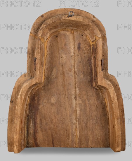 Fragment of a sarcophagus lid. Part of the lid of an anthropoid woman's sarcophagus. Large, striped wig falling on the breasts at the front, decorated with four diadems of lotus petals and vulture wings, and bands of rosettes at the ends. On the breast is a multi-row necklace, with lotus flowers and rosettes forming the lower row. Lotuses, vulture vulture wings, element of the so-called vulture diadem, necklace, wigs, funerary equipment, lotus flower decorative motif. Egyptian art. c. 945–c. 735 BC; Third Intermediate Period, 22nd Dynasty, Egypt. Sarcophagus. Height 62 cm, width 49 cm, depth 20 cm., A carved wooden object with a rounded top and stepped sides, showing a worn, rough surface and visible grain; the wood varies in shades of brown with lighter tan highlights along edges and recessed grooves, and a few darker brown streaks and patches; there is a small metal hanging loop near the top center showing a gray-silver color; the background is a flat light gray.