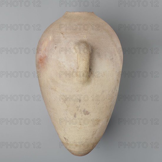 Large ovoid amphora with rounded foot, clay MD-type marl, Vienna System; body wheel-made, foot hand-made; surface even; color very light brown. Two small vertical handles placed at widest point near base of the sloping neck; neck and spout missing. Sloping handles symmetrically painted with black ink inscriptions labels/dockets. Above one handle, slightly toward center, are impressed cartouches of Hatshepsut and Thutmose III and a snake hieroglyph dz. Under one handle a potter’s mark of two intersecting lines. New Kingdom, 18th Dynasty reign of Hatshepsut and Thutmose III, ca. 1550–1295 BC; provenance: Deir el-Medina grave 1370 f. Preserved height 49.5 cm; belly diameter 30.5 cm. Analogies: amphora from the tomb of Hatnefer and Ramose with hieratic inscription dating to year 7 of the joint reign; R. Holthoer, New Kingdom pharaonic sites., A large, elongated clay vessel with a rounded top and tapered bottom is shown against a smooth background. The vessel has a single short handle attac...