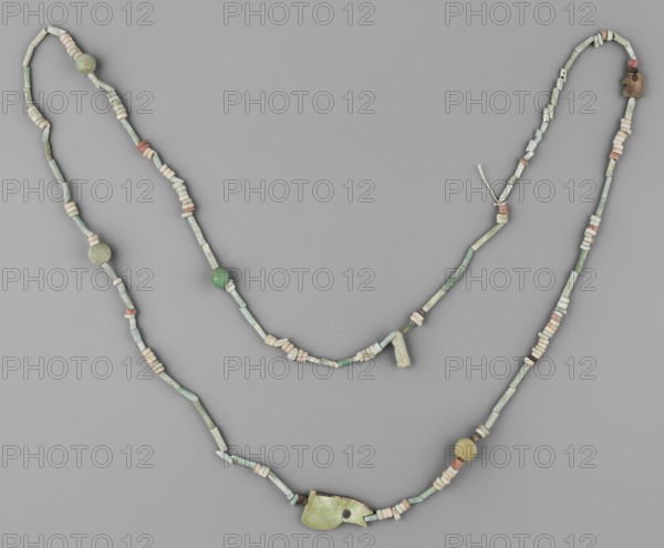 Necklace, Necklace consisting of 67 straw-shaped beads, 117 flat rings, 10 double flat rings with two holes, 4 balls, 2 udjat eyes 1 eyelet in 2 parts, 1 deity figurine without preserved feet. Predominant color: green; some beads brick-red, brown, and white. Late Period, Egypt, 664–332 BC. Amulet/jewelry; height 98 cm., A beaded necklace arranged against a neutral gray background, composed of a mix of cylindrical and disc-shaped beads and a few larger spherical beads, with a larger irregular pendant-like piece near the lower center; the beads show colors including various shades of green, pale green, off-white, beige, and touches of muted reddish-brown, with a small knot of light-colored string visible near the upper right.