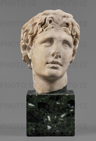Head of Alexander the Great, unknown Roman workshop. Alexander III the Great King of Macedonia; 356–323 BC. Male portrait, Roman sculpture, Roman copy from a Greek original; head. The head of a young man is clearly turned to the left in a pathetic manner. The head is reflected at the base of the neck. The face is oval, the skeletal structure is not emphasized. The mouth is prominent, with slightly parted lips. The nose is straight, reflected at the tip. The eyes are almond-shaped, deep-set, and the eyebrows are expressive, protruding strongly above the eyeball. The forehead is flat, low, and covered with lush locks of hair. The hairstyle consists of loosely arranged, slightly curled locks. Above the forehead, shifted off-axis to the right, a lock of hair is visible, radiating outwards, slightly raised and clearly different from the other locks. At the back of the head, the hair is arranged in wavy locks, with only the lower part being freely arranged. Date: 140–160 AD formerly dated 15...